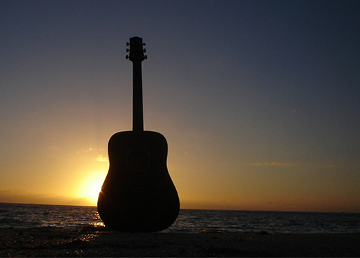 Guitar on a beach during sunset