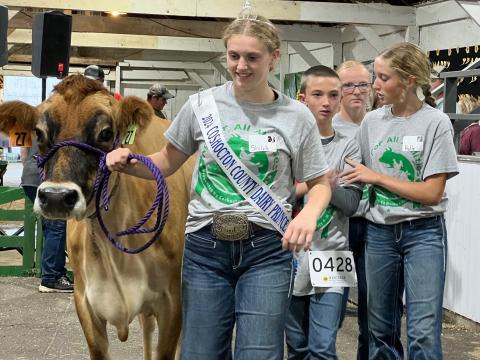 Kenton Wilson walks with a cow and several mentors at Coshocton County's inaugural Ag for All Abilities Livestock Show.